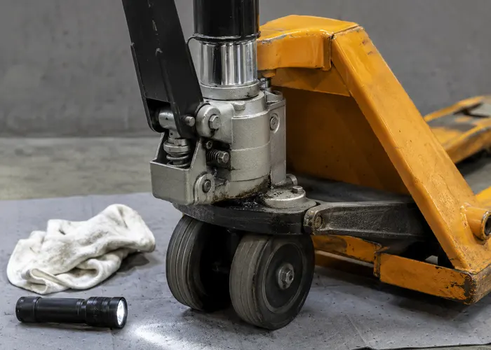 Inspeção de vazamento de óleo no conjunto hidráulico de uma paleteira manual