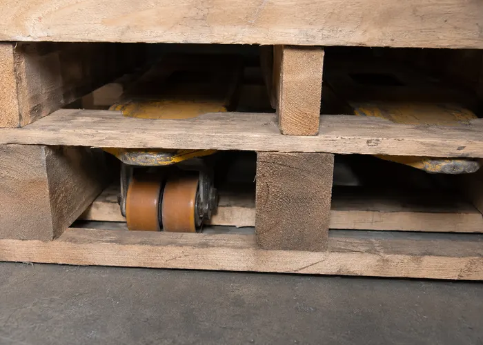Roda de carga da paleteira encontrando uma travessa inferior dentro do pallet